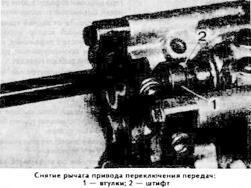 Сдвиньте втулку 1 (см. фото), выбейте штифт 2 и снимите рычаг привода переключения передач.
