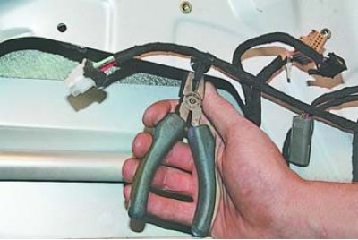 6. Отсоедините держатели жгута проводов от внутренней панели передней двери.