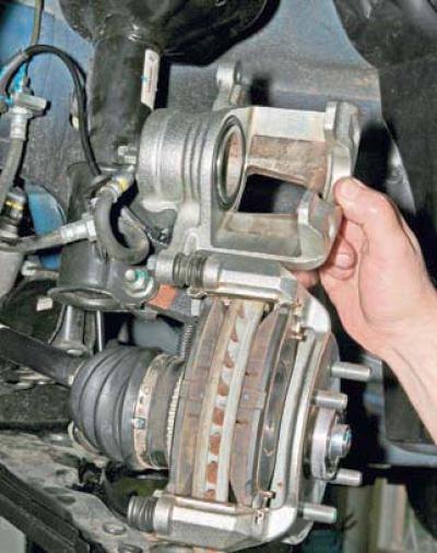 Приподнимаем суппорт, поворачивая его вокруг оси верхнего направляющего пальца.