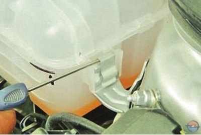 6. Подденьте отверткой фиксатор крепления расширительного бачка к кронштейну…